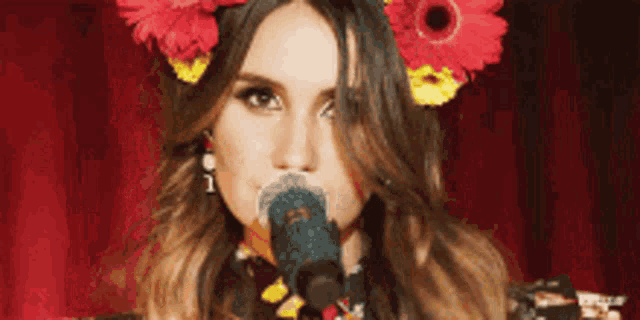 a woman is singing into a microphone with a flower in her hair .