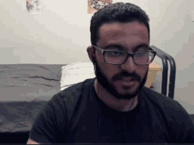 a man with a beard wearing glasses and headphones looks at the camera
