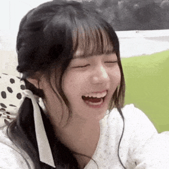 a young woman is laughing with her eyes closed and her mouth open .