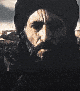 a man with a beard wearing a turban is riding a black horse