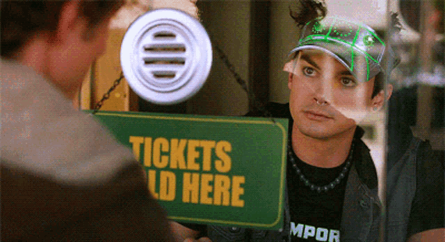 a man looking at a tickets sold here sign