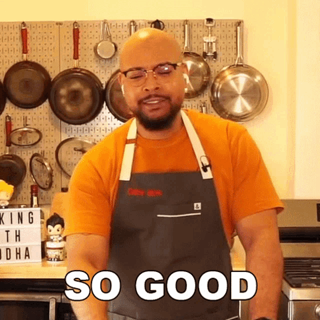 a man wearing an apron says so good in front of a wall of pots and pans
