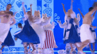 a group of people in costumes are dancing on a stage with a blue background .