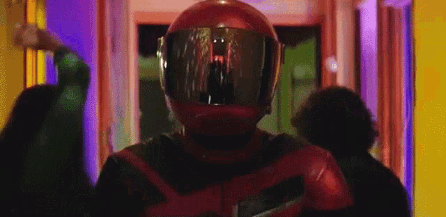 a man wearing a red motorcycle helmet is standing in a hallway