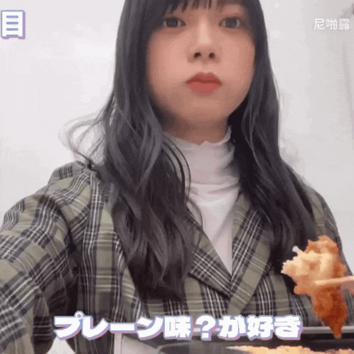 a girl in a plaid jacket is holding a piece of food in her mouth