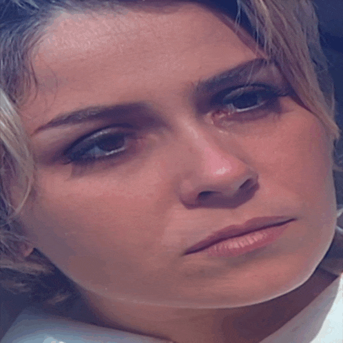 a close up of a woman 's face with a tear coming out of her eye