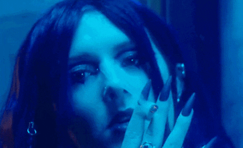 a woman with long black nails and a nose ring is smoking a cigarette