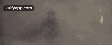 a man in a leather jacket is holding a gun in his hand in a dark room .