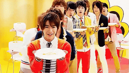 a group of young men are standing in a line holding plates of food .