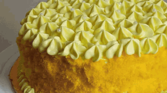 a yellow cake with yellow frosting and white pearls