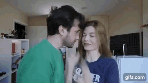 a man and woman are kissing in a living room .