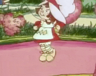 a strawberry shortcake cartoon character is standing on a pink surface in a garden .