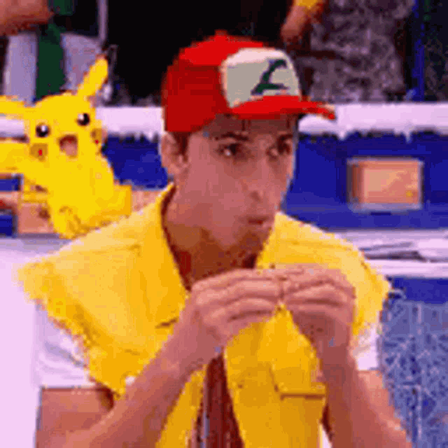 a man wearing a red hat and a yellow vest is eating a sandwich
