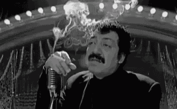 a man is smoking a cigarette in front of a microphone .