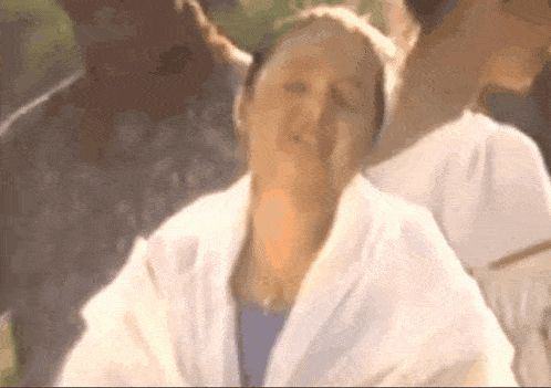 a woman in a white robe with her eyes closed and a man behind her