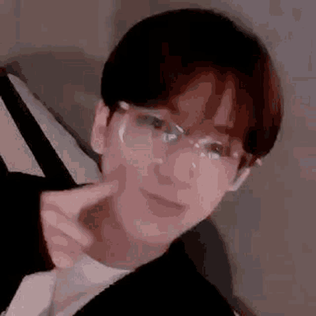 a close up of a person wearing glasses and making a peace sign .