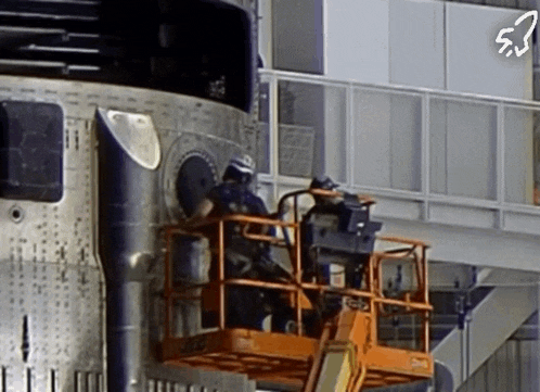 a rocket is being worked on by two men on a lift with the number 5 on the bottom right