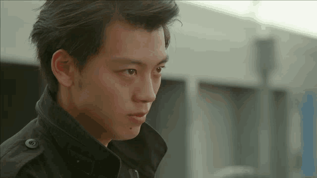 a young man wearing a black jacket has a button on his collar that says ' a ' on it