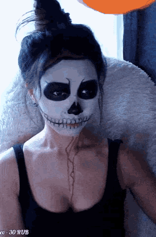 a woman with a skeleton face painted on her face is sitting in front of an orange balloon
