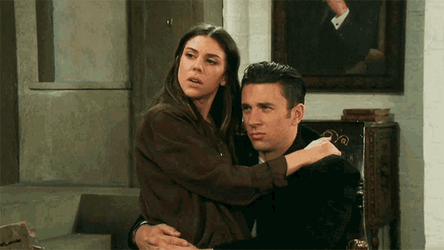 a woman is hugging a man in front of a painting of a man