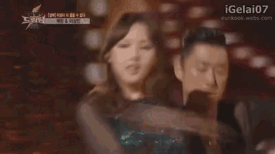 a man and a woman are dancing together on a stage in a dark room .