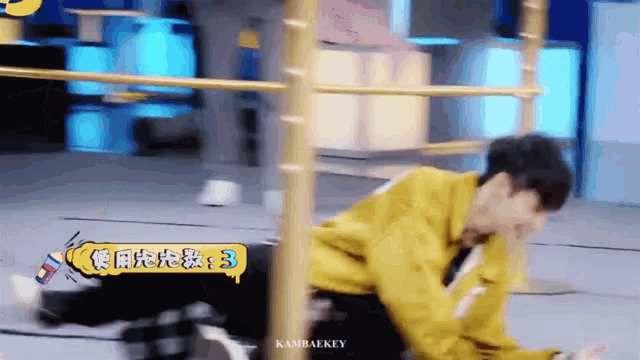 a young man in a yellow jacket is laying on the ground .