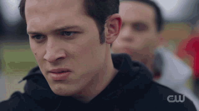 a close up of a man 's face with a cw logo in the background