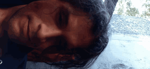 a close up of a man 's face with his eyes closed and his hair blowing in the wind