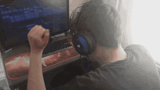 a man wearing headphones looks at a computer monitor