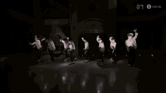 a group of young men are dancing in front of a clock that says xii