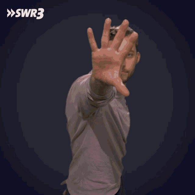 a man is making a stop sign in front of a blue background with swr3 written on it