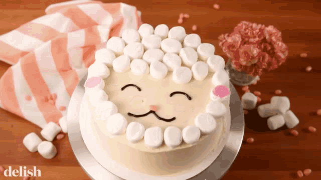 a cake decorated to look like a sheep with marshmallows around it