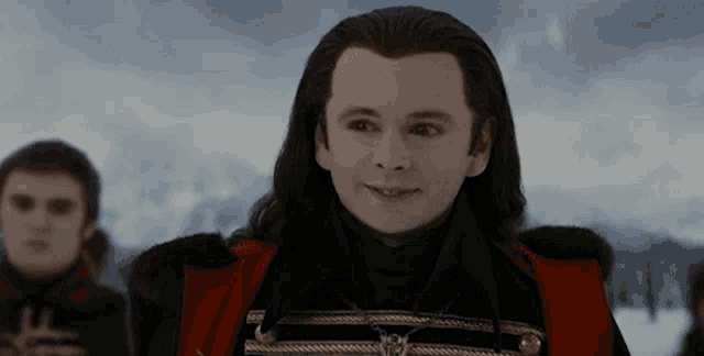 a man with long hair is wearing a black and red jacket