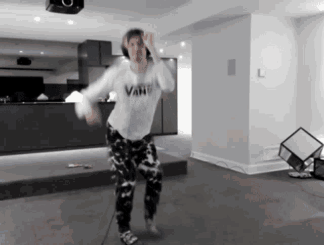a person in a vans shirt is dancing in a room