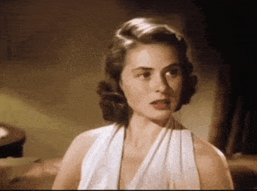 a woman in a white dress looks at the camera with her mouth open