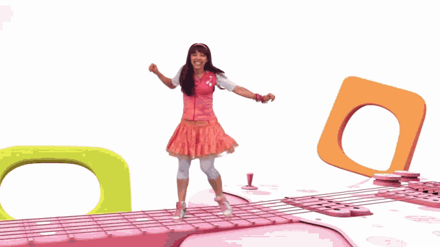a girl in a pink dress is dancing on a pink carpet