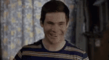 a young man in a striped shirt is smiling and looking at the camera .
