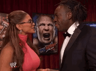 a man and a woman are standing next to each other in front of a poster of brock lesnar