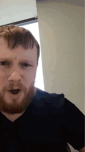 a man with a beard and a black shirt is making a funny face