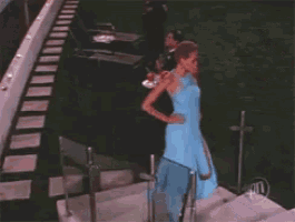 a woman in a blue dress walks down stairs
