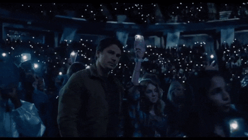 a man stands in front of a crowd of people holding their phones up