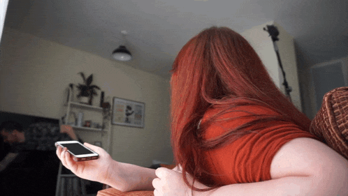 a woman laying on a couch holding a cell phone