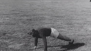 a man is doing push ups on the grass in a field .