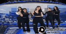 a group of women are dancing on a stage with snack video logo in the corner