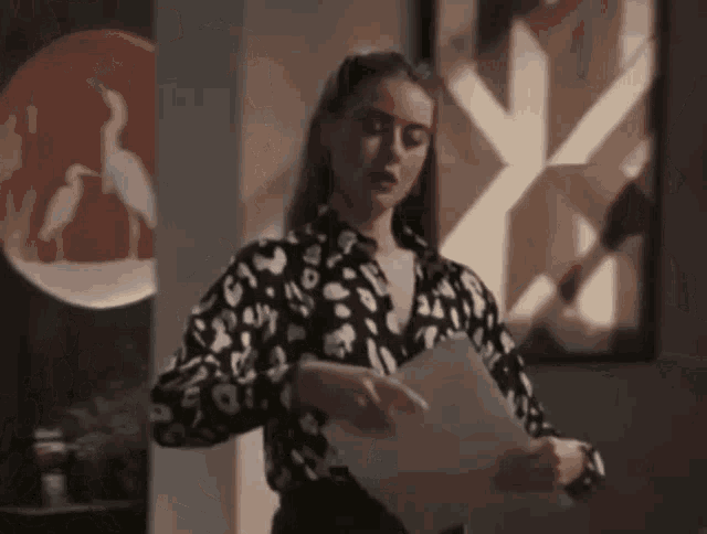 a woman in a black and white leopard print shirt holds a piece of paper