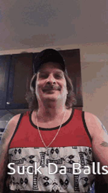 a man wearing a red tank top and a black hat says " suck da balls "