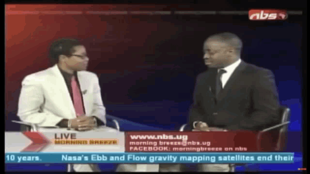 two men are sitting in front of a screen that says nbs