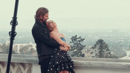a man and a woman are hugging each other on a balcony