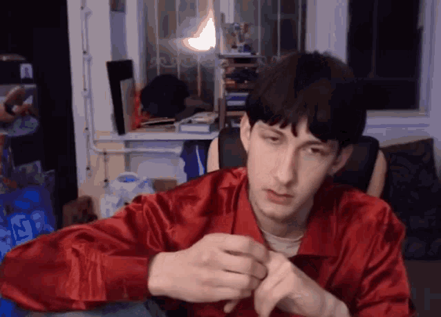 a man in a red shirt is sitting in front of a window