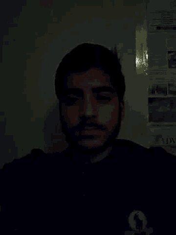 a man with a beard is standing in the dark in front of a wall with papers on it including one that says mix